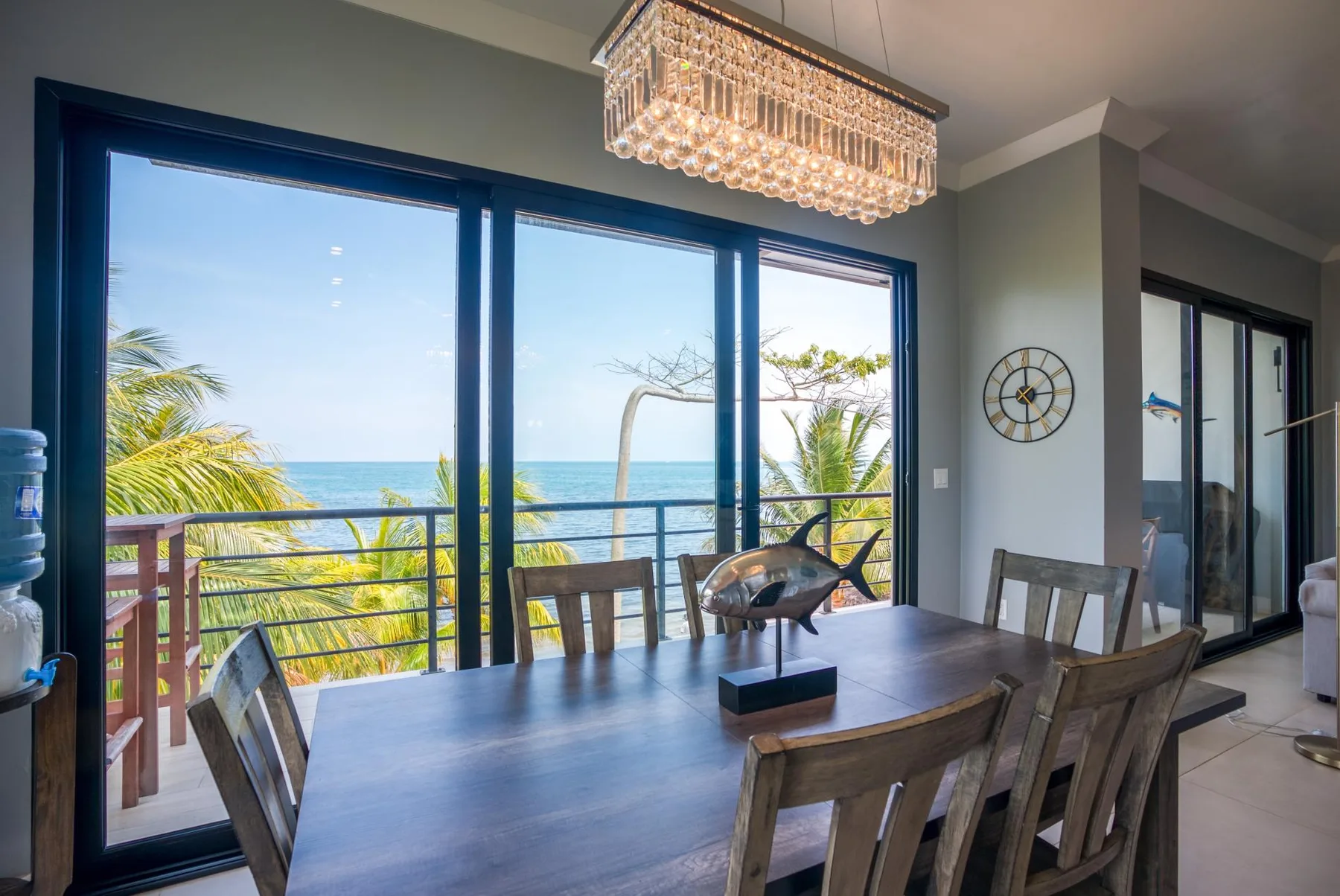 Un comedor con una mesa junto a grandes ventanales con vistas al océano.