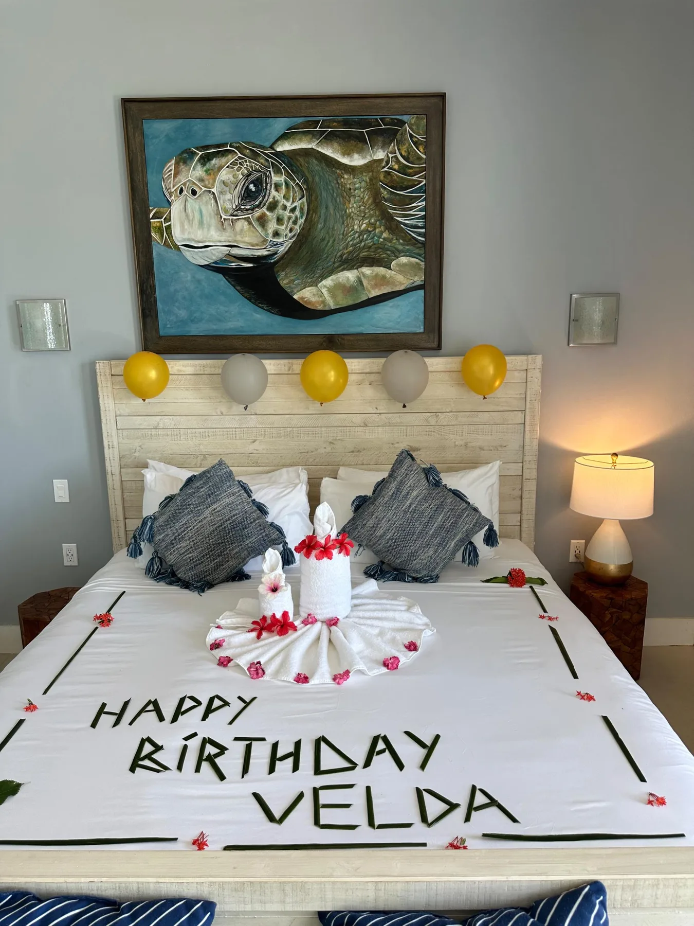 Un dormitorio con una cama decorada con letras de cumpleaños y una pintura de una tortuga marina encima.
