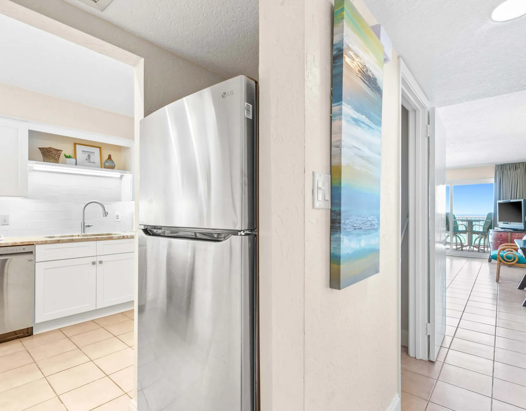 Una cocina luminosa con gabinetes blancos y un refrigerador de acero inoxidable.