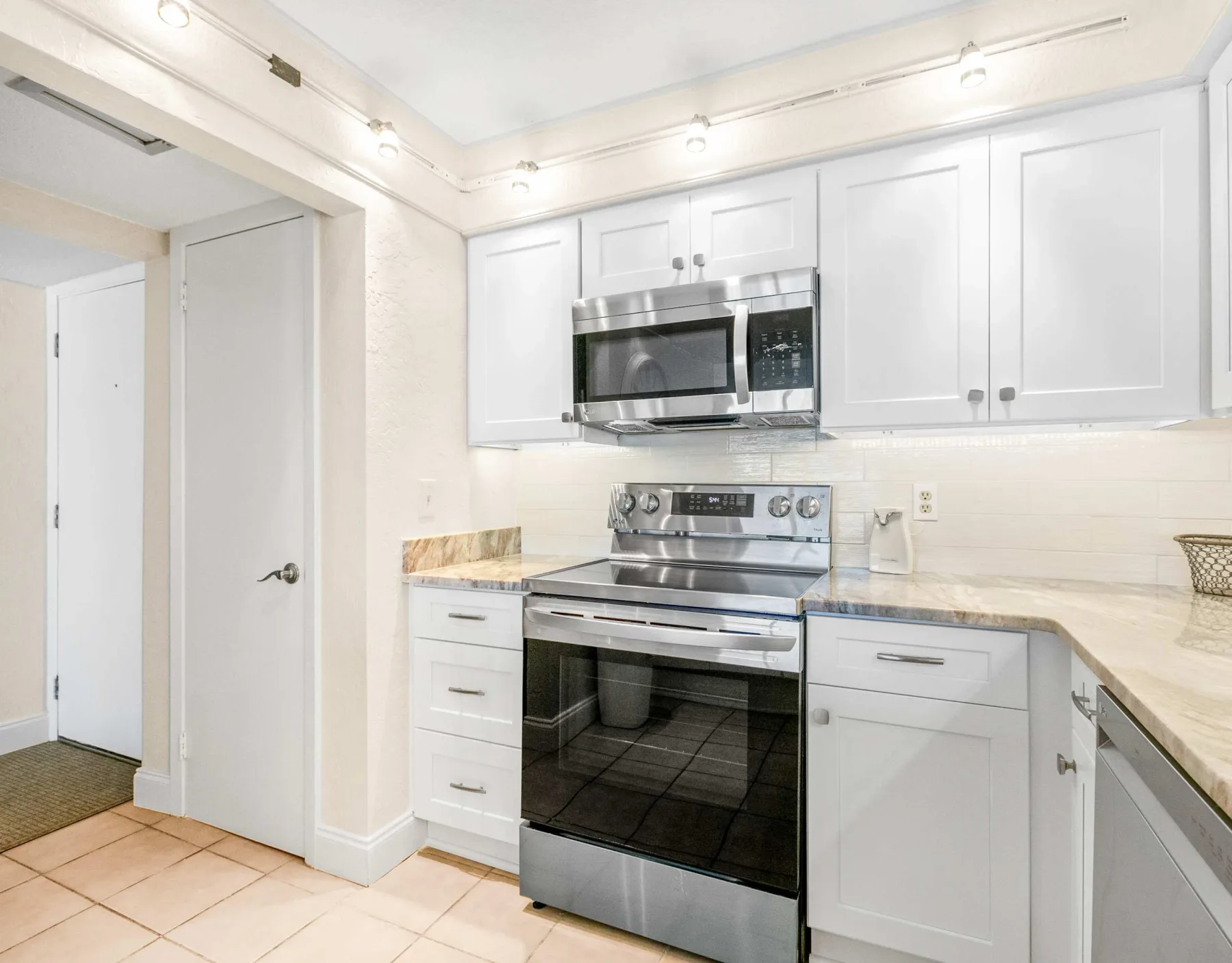 Una cocina luminosa con gabinetes blancos, microondas y estufa.