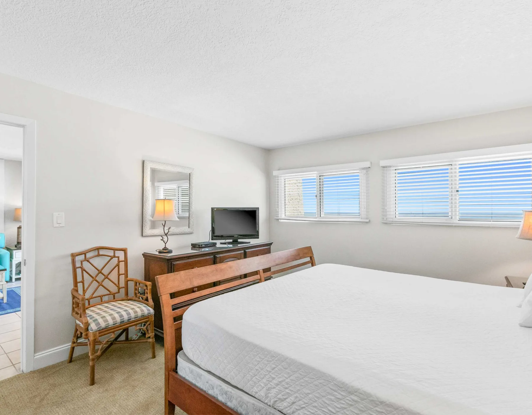 Un dormitorio con una cama, asientos de madera y ventanas con persianas.