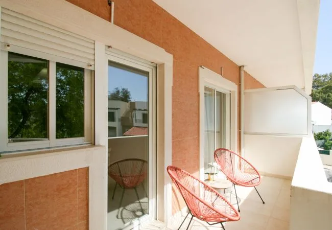 Un balcón soleado con una puerta de vidrio y asientos al aire libre.