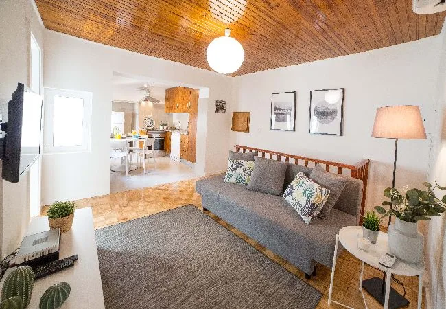 A living room with gray seating, a rug, and an open kitchen beyond.