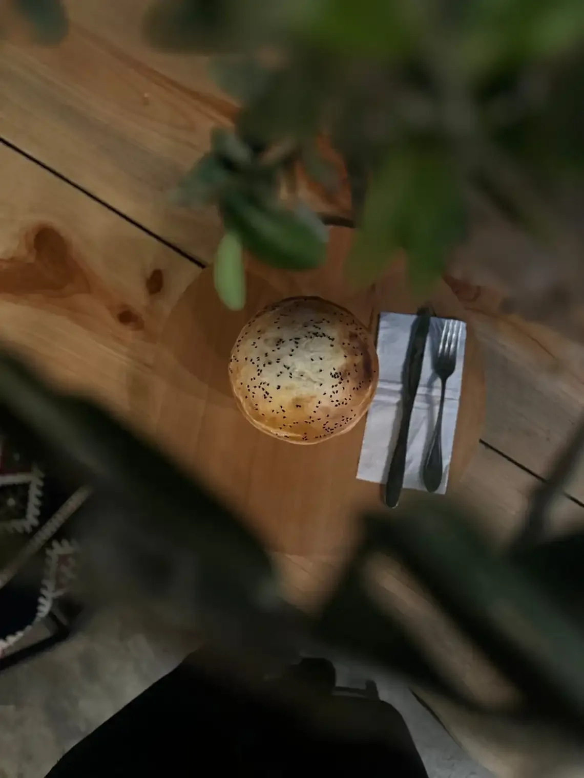 Espacio representativo del hotel: Una mesa de comedor tiene pan redondo con semillas y cubiertos junto a una planta.