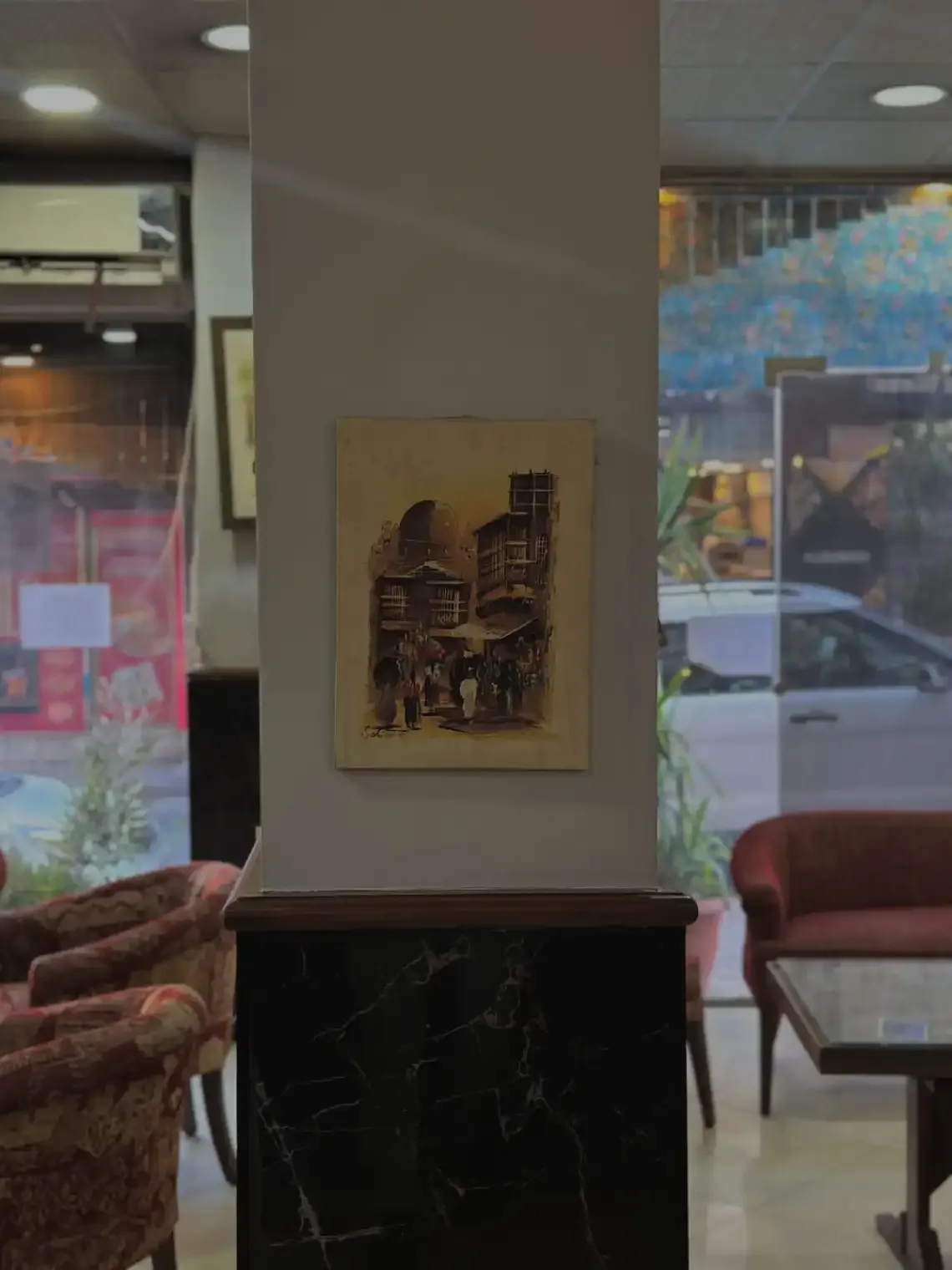 Espacio representativo del hotel: Una zona de descanso del vestíbulo tiene asientos estampados, una mesa y una obra enmarcada.