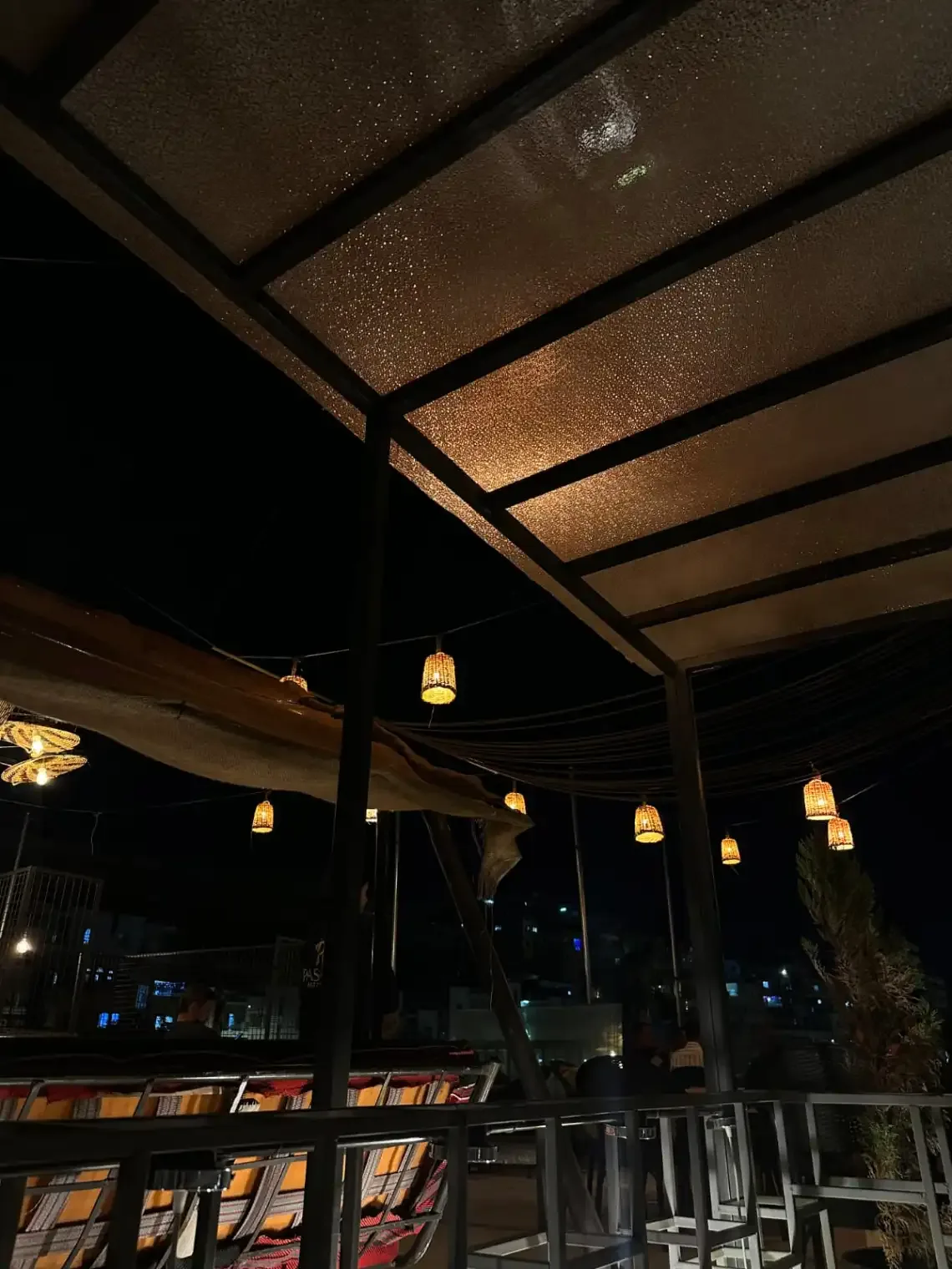 Espacio representativo del hotel: Una zona de estar exterior cubierta se ilumina con faroles colgantes por la noche.