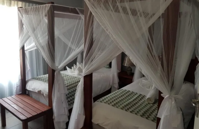 Espacio representativo del hotel: Un dormitorio con camas con dosel cubiertas de mosquiteros blancos.