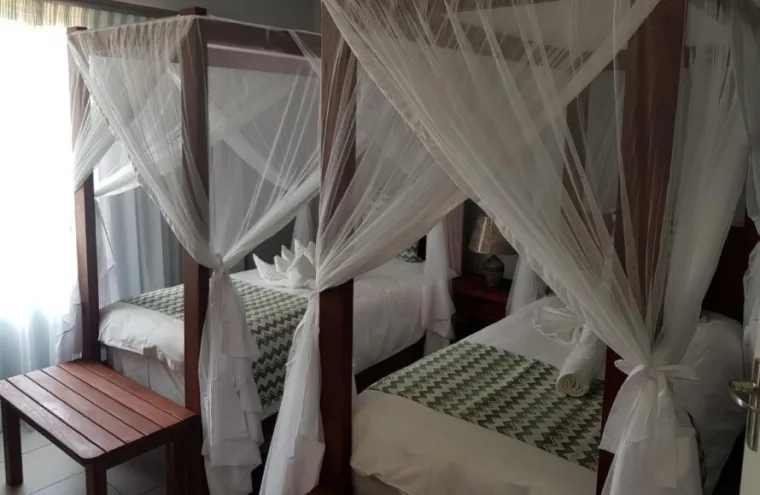 Espacio representativo del hotel: Un dormitorio con camas con dosel y cortinas blancas translúcidas.