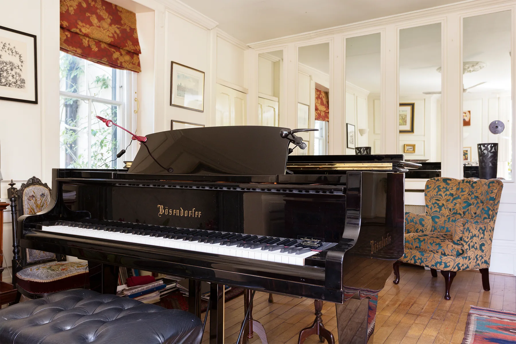 Una sala de piano con un piano de cola negro y asientos estampados.