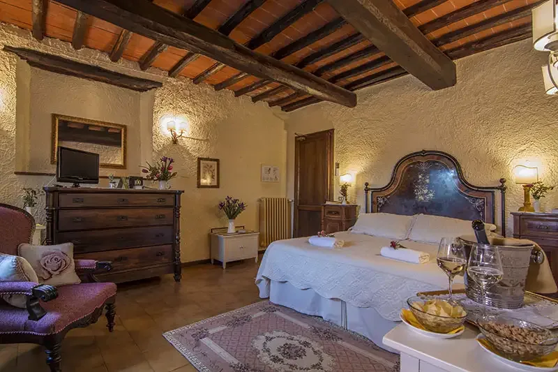 Espacio representativo del hotel: Un dormitorio con una cama grande, una cómoda de madera y vigas vistas en el techo.
