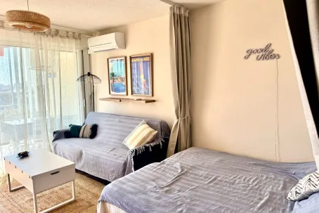 Un dormitorio luminoso con una cama y un sofá junto a grandes ventanas.