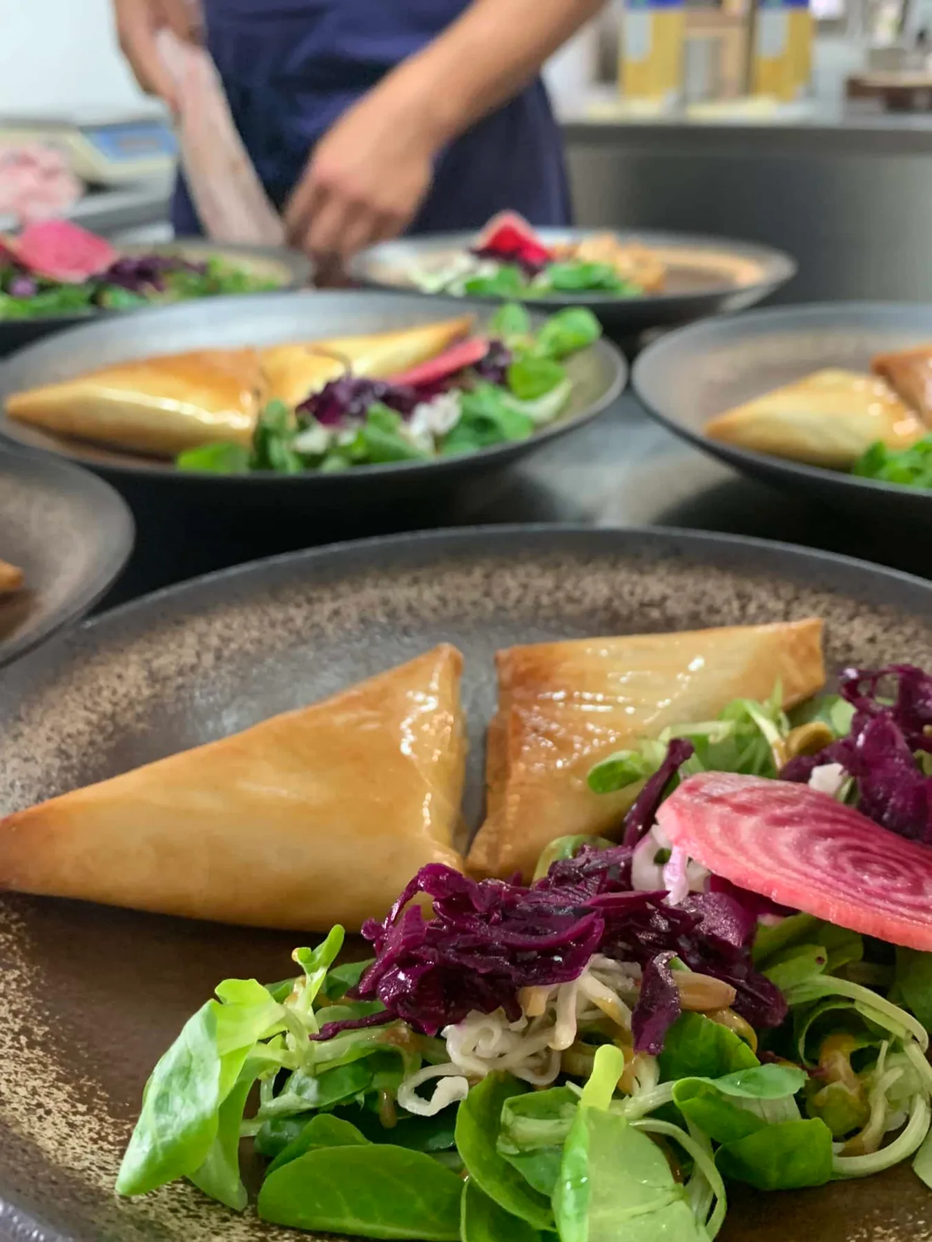 Representative hotel space: Prepared plates of food with salad sit on a counter while a worker arranges them.