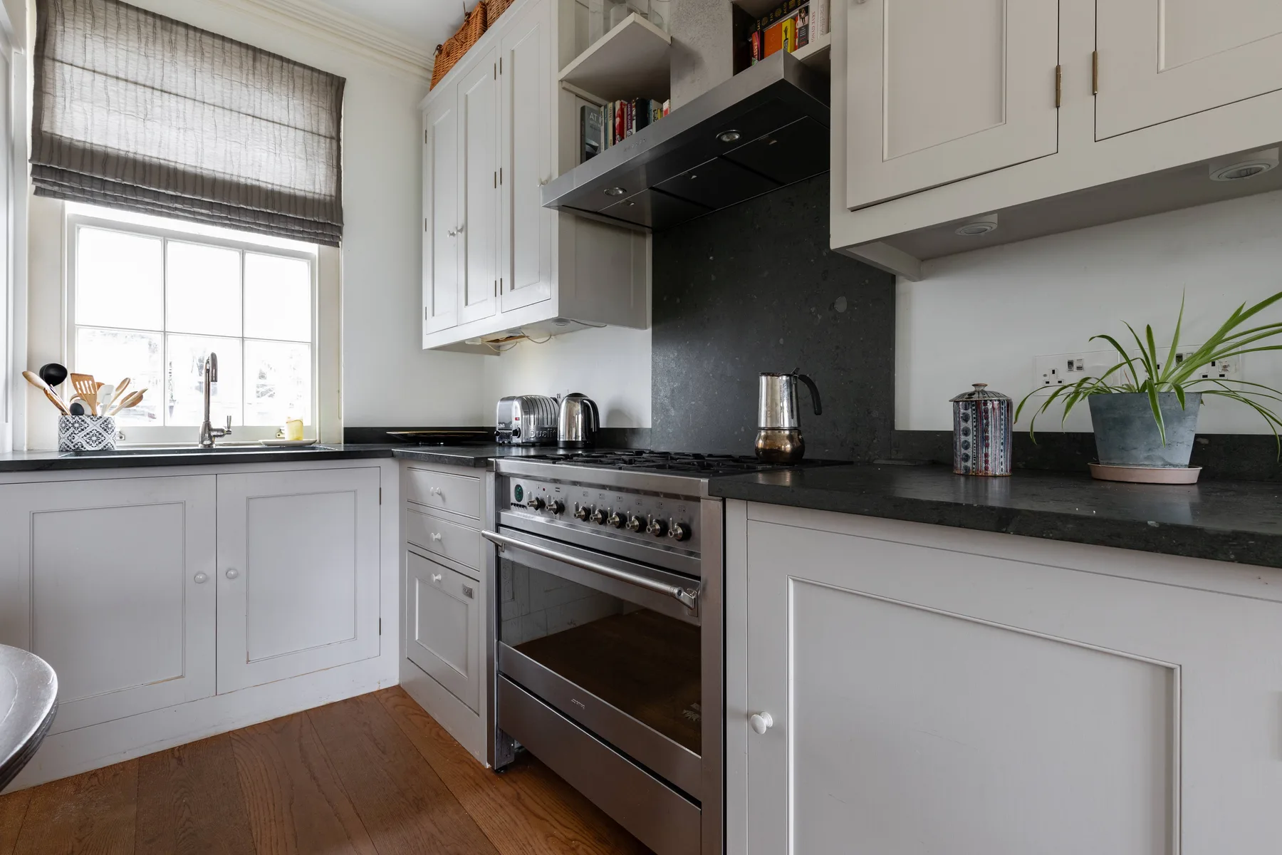 A bright kitchen with white cabinets, dark countertops, and a stainless-steel range.