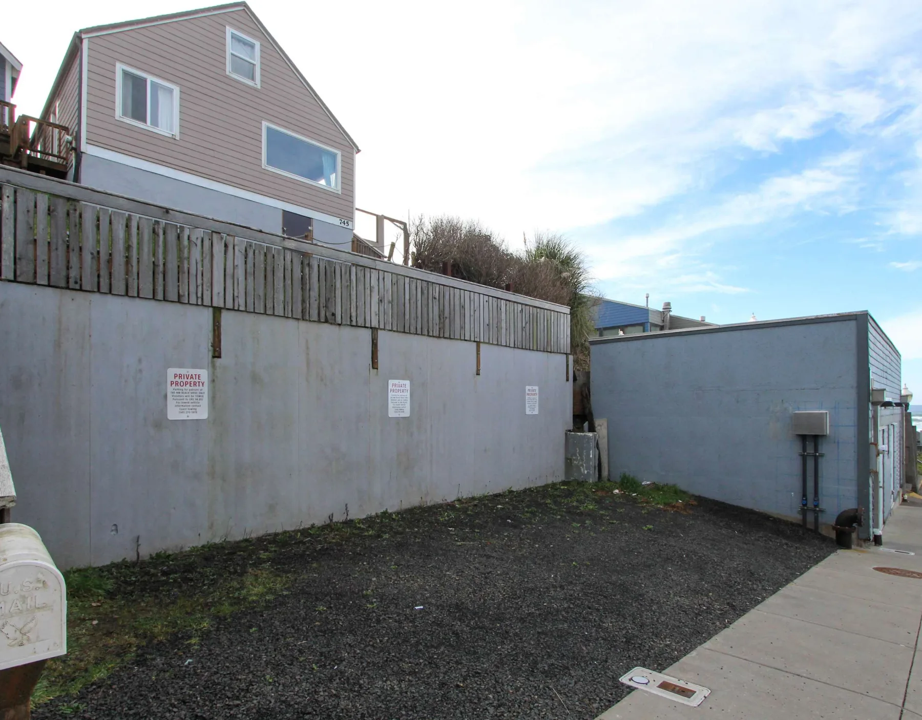 An outdoor paved area beside a concrete retaining wall and buildings.