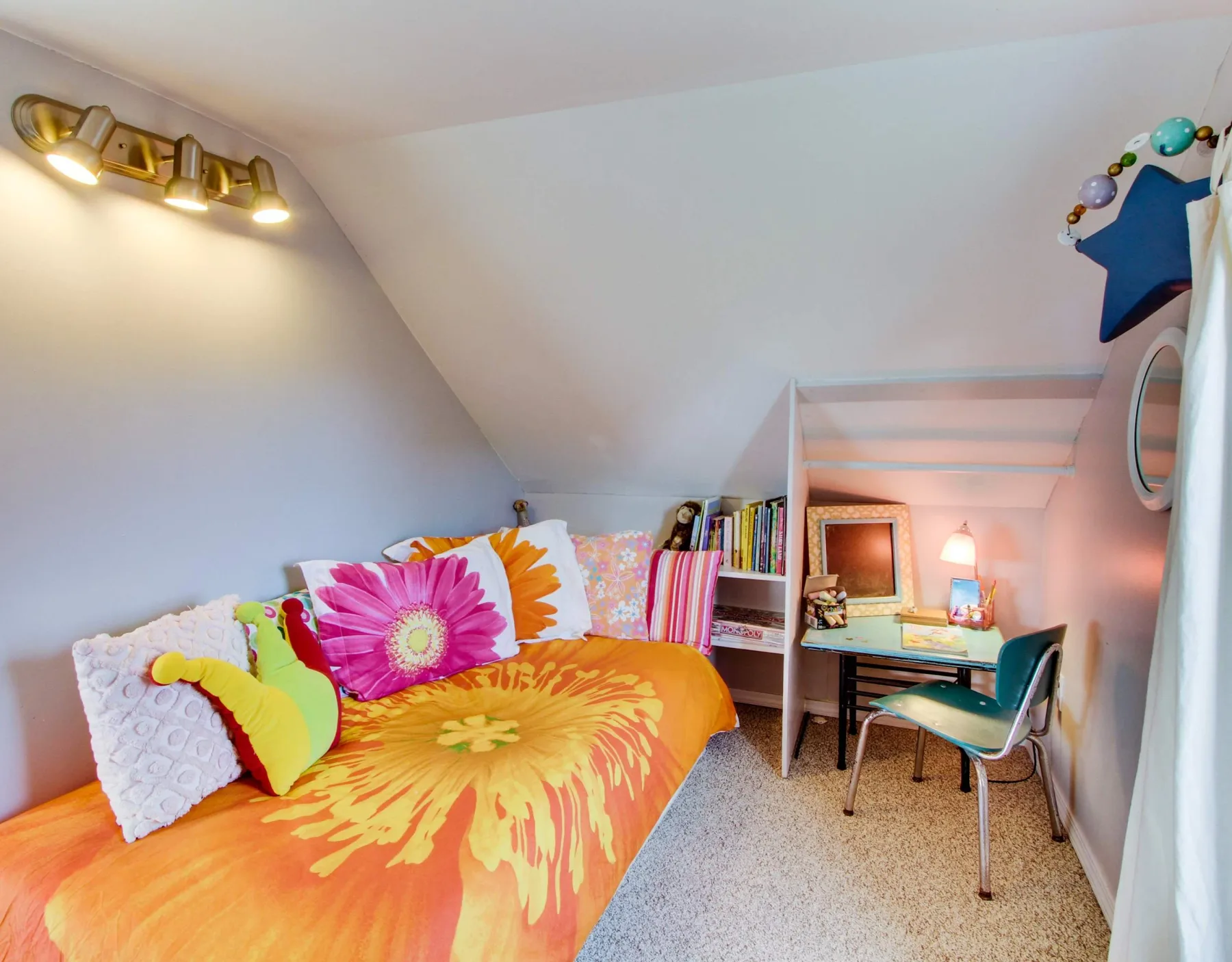 A colorful bedroom with bright floral bedding and a small desk.
