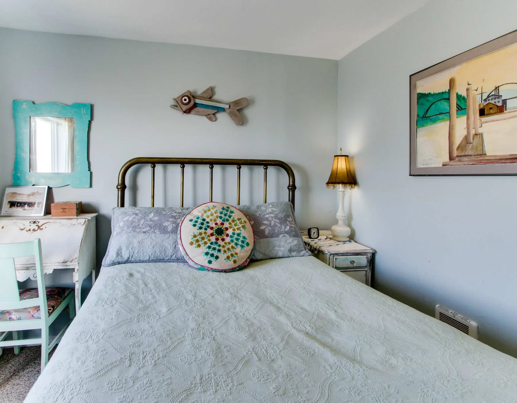 A bedroom with a metal bed, patterned pillows, and a bedside lamp.