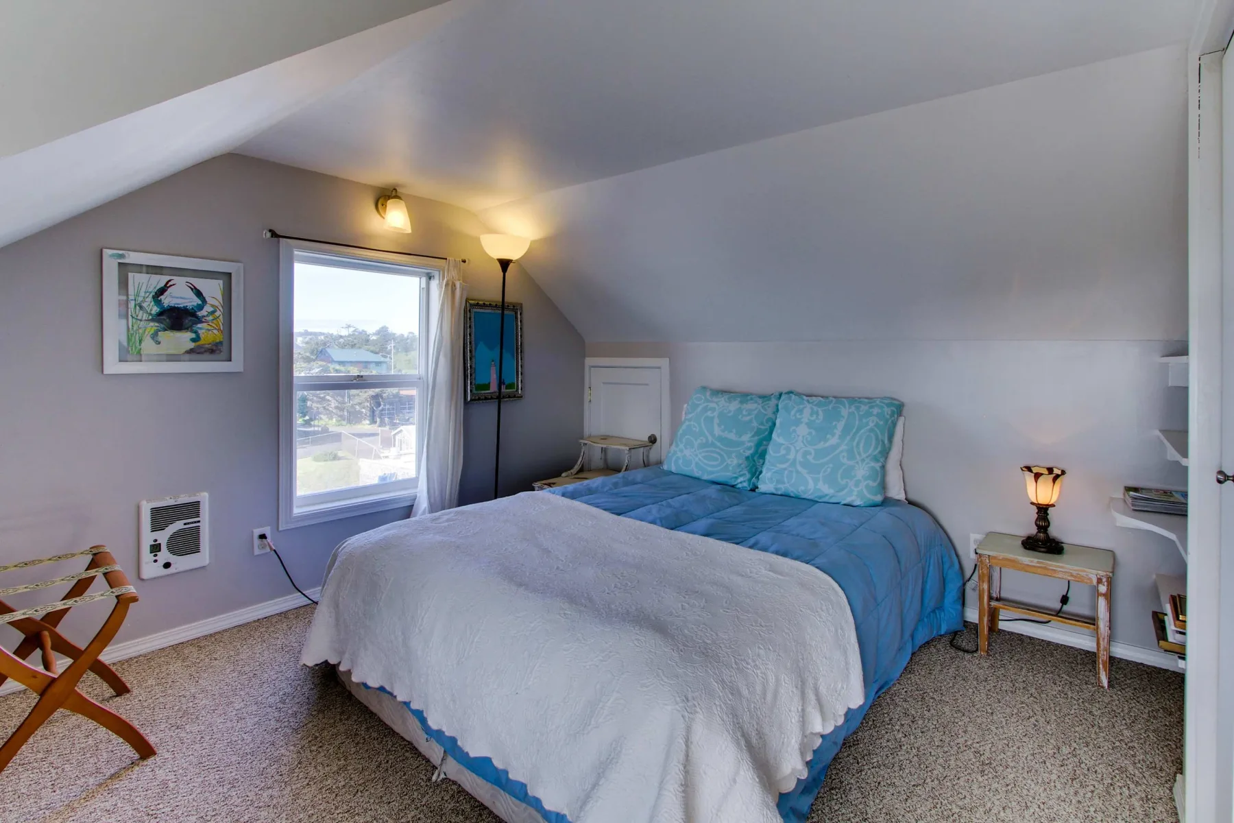 A bedroom with a bed beneath a sloped ceiling and a window beside it.