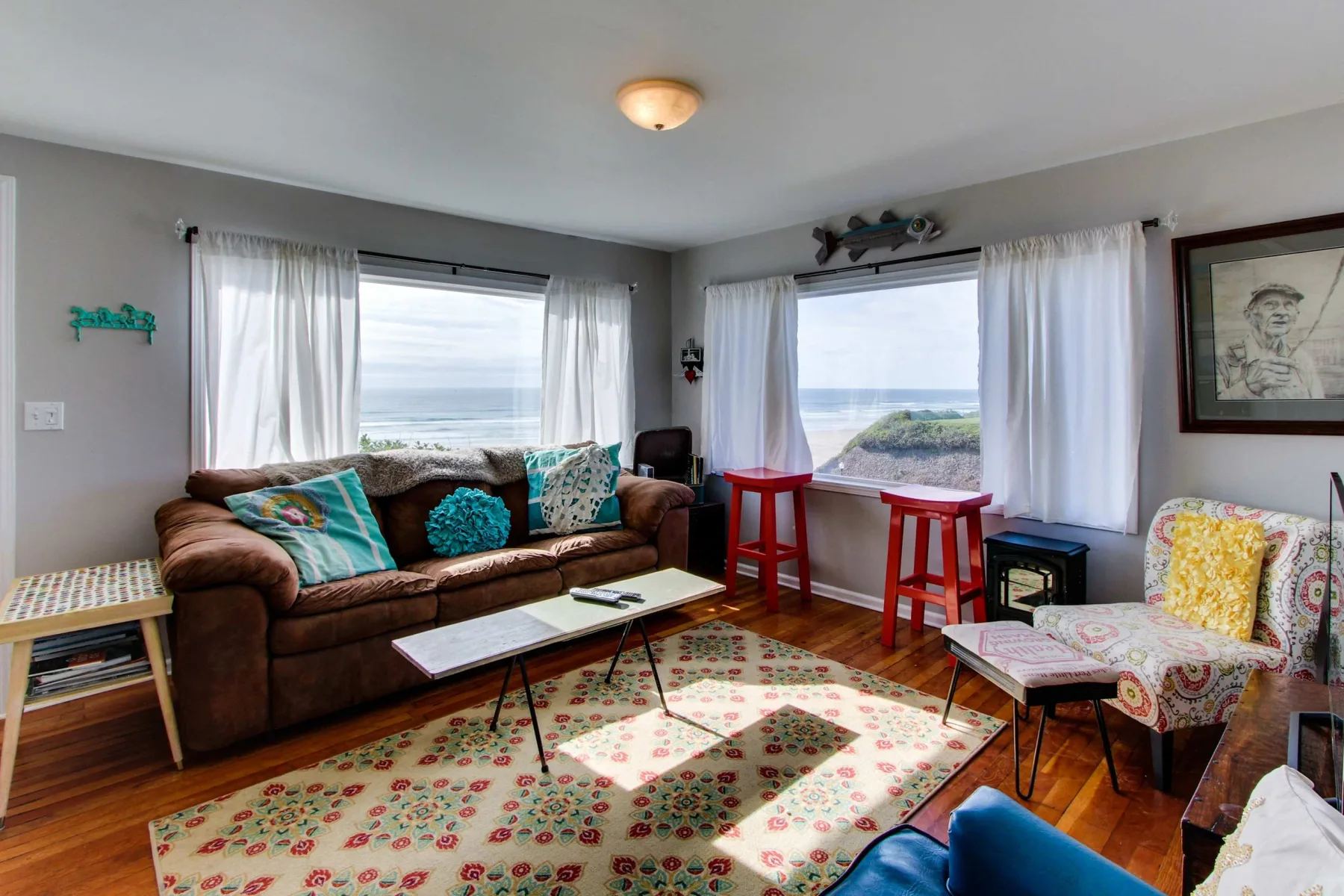 A living room with seating, a coffee table, and large windows overlooking the water.