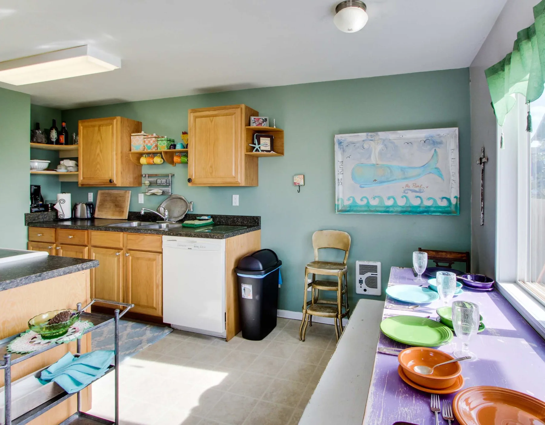 A kitchen with wooden cabinets and a dining table set with colorful dishes.