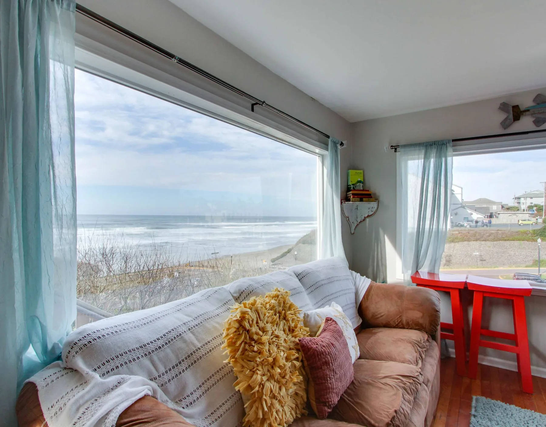 A living room with seating beside large windows overlooking the ocean.