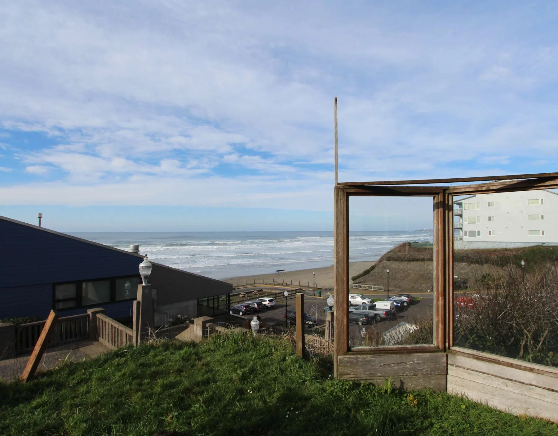 A coastal view overlooks the beach and ocean from a grassy hillside.