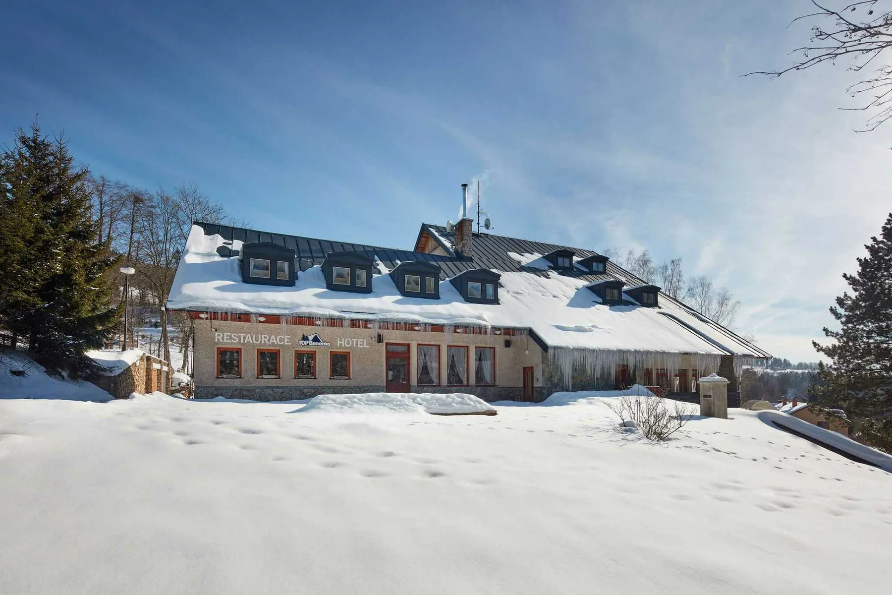 Espacio representativo del hotel: Un edificio de hotel cubierto de nieve se alza junto a un amplio paisaje nevado.