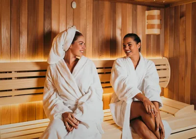 Espacio representativo del hotel: Una sauna de madera con dos personas sentadas en un banco.