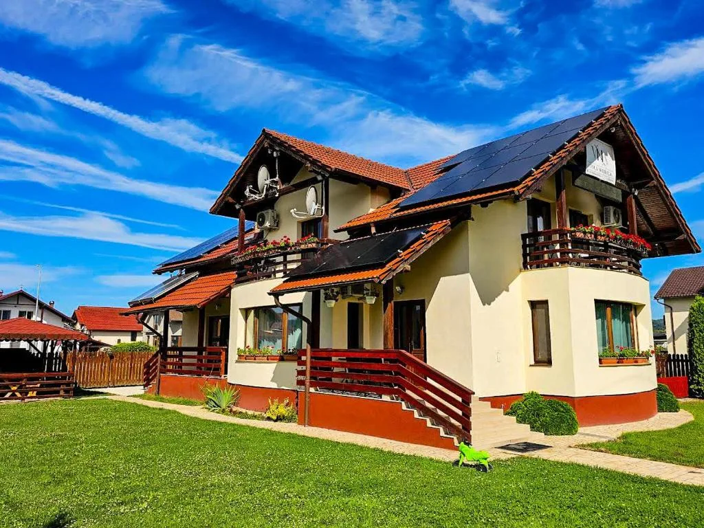 Espacio representativo del hotel: Una casa de varios niveles con balcones se alza junto a un césped verde.