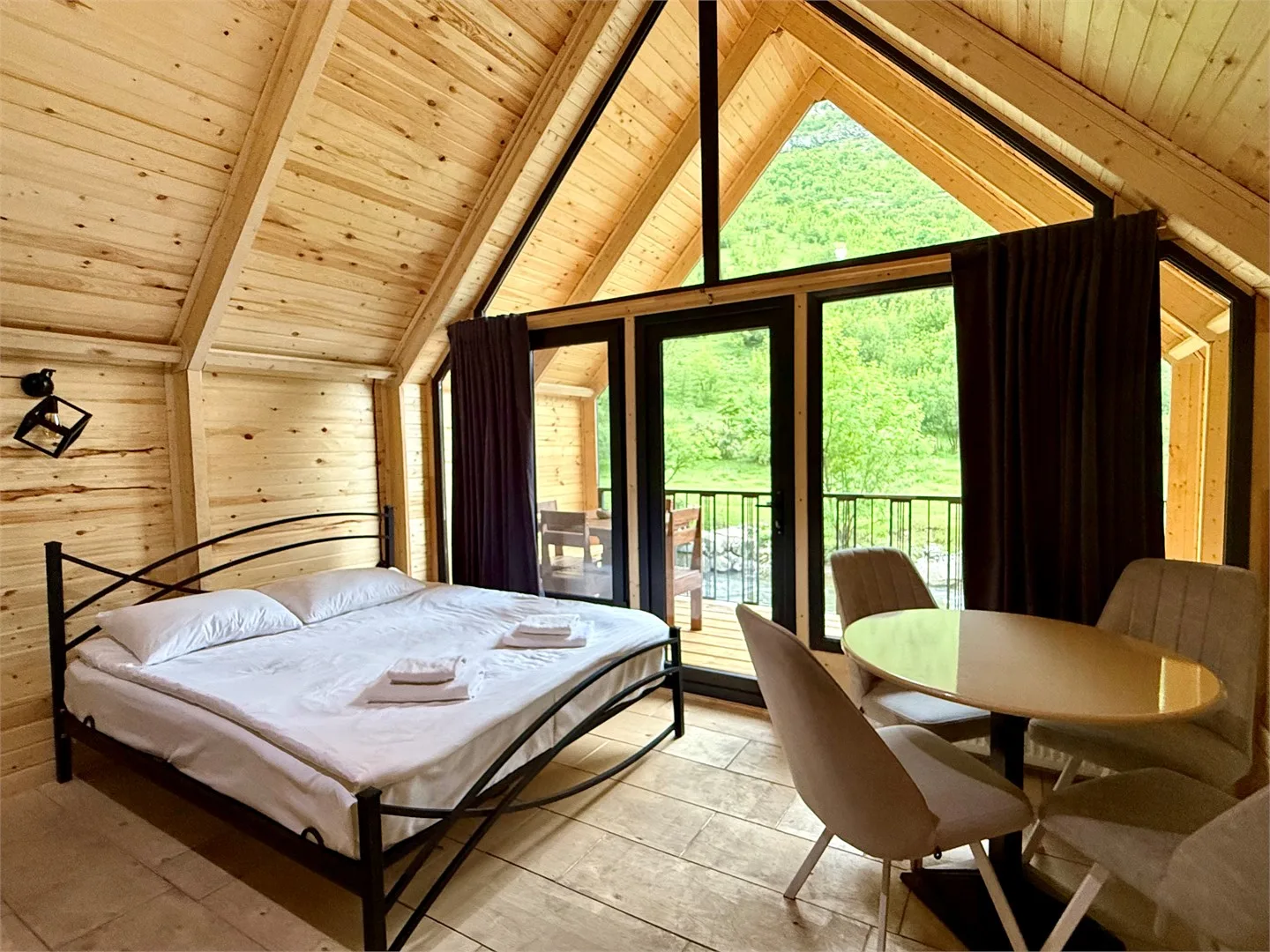Representative hotel space: A wood-paneled bedroom with a bed, dining table, and glass doors opening to greenery.