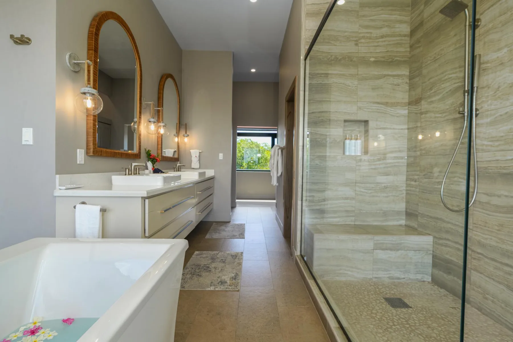 A spacious bathroom with a bathtub, double vanity, and glass-enclosed shower.