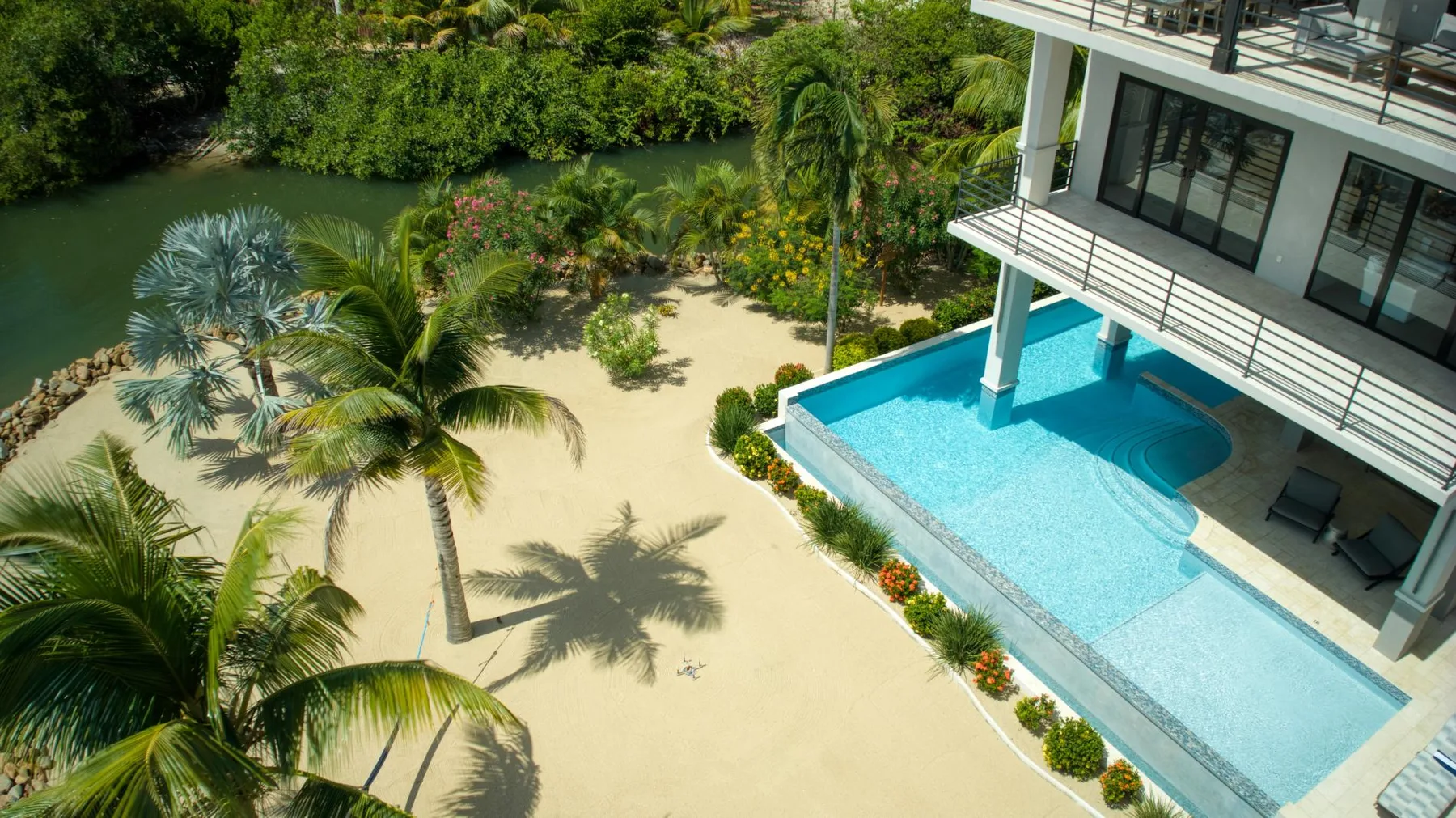 A swimming pool beside a sandy garden and a modern building.