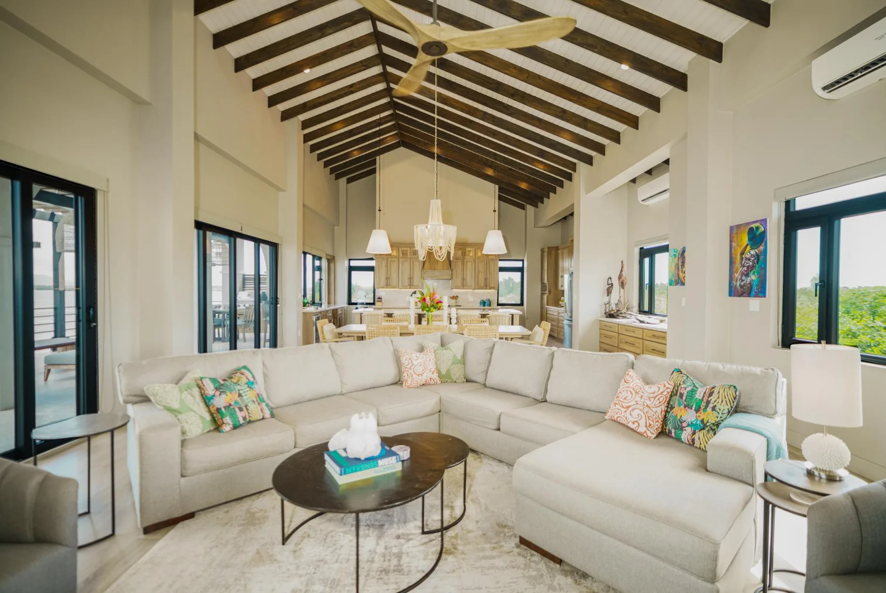 A bright living room with a large sectional seating area and an open kitchen beyond.