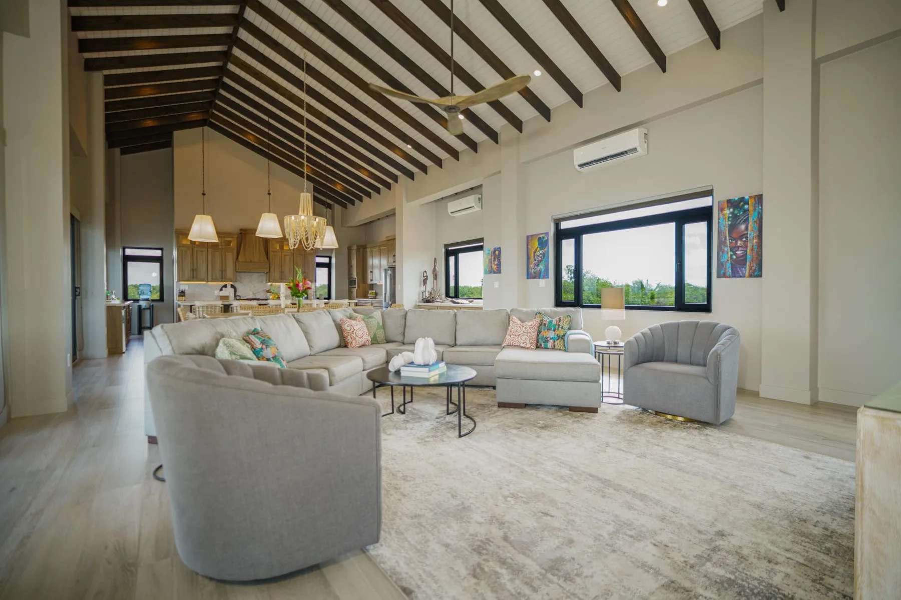 A spacious living room with seating around a coffee table beneath a high beamed ceiling.