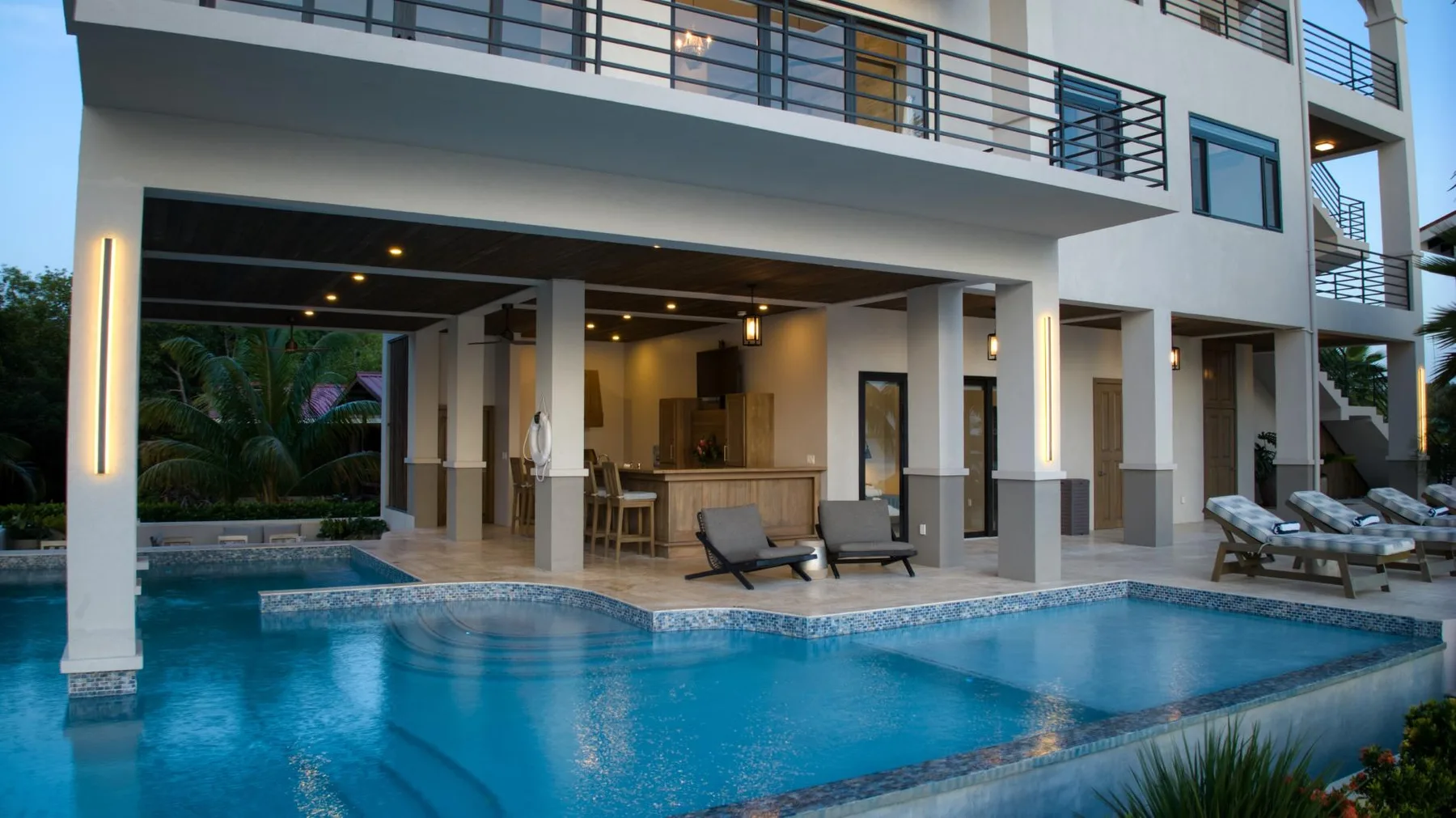 A swimming pool beside a covered outdoor seating area at a modern building.