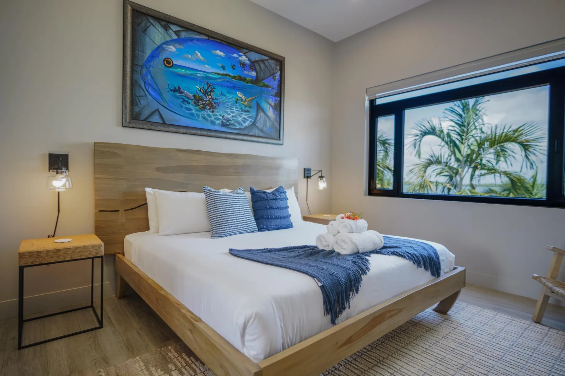 A bedroom with a wood-framed bed dressed in white linens and blue accents.