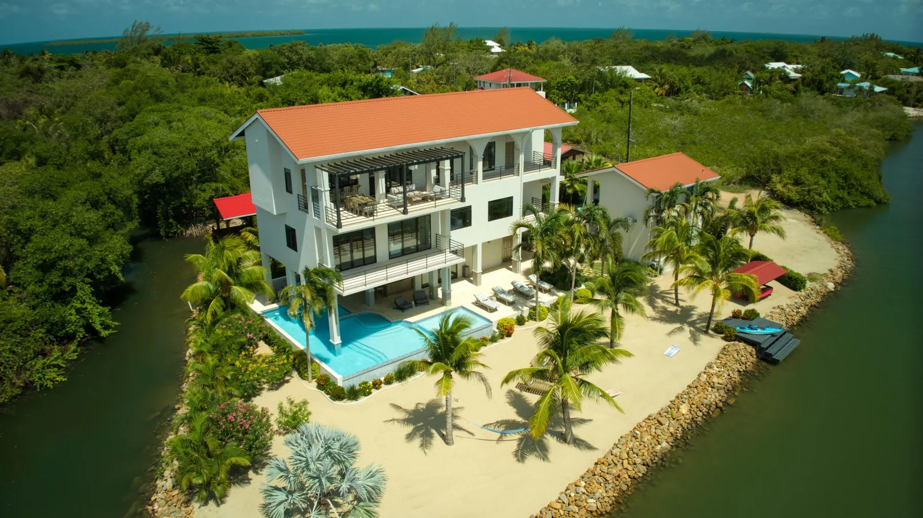 A beachfront-style property with a multi-story building, pool, and surrounding greenery.