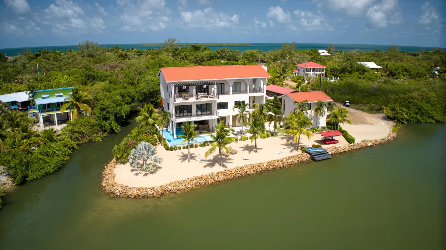 An aerial view of a waterfront property with white buildings and a sandy shoreline.
