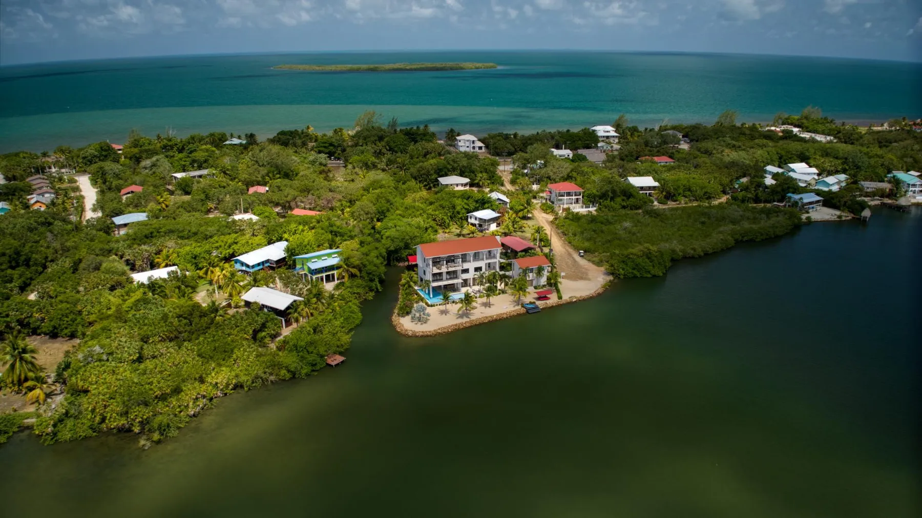 Aerial view of a coastal settlement beside a lagoon, with the ocean beyond.