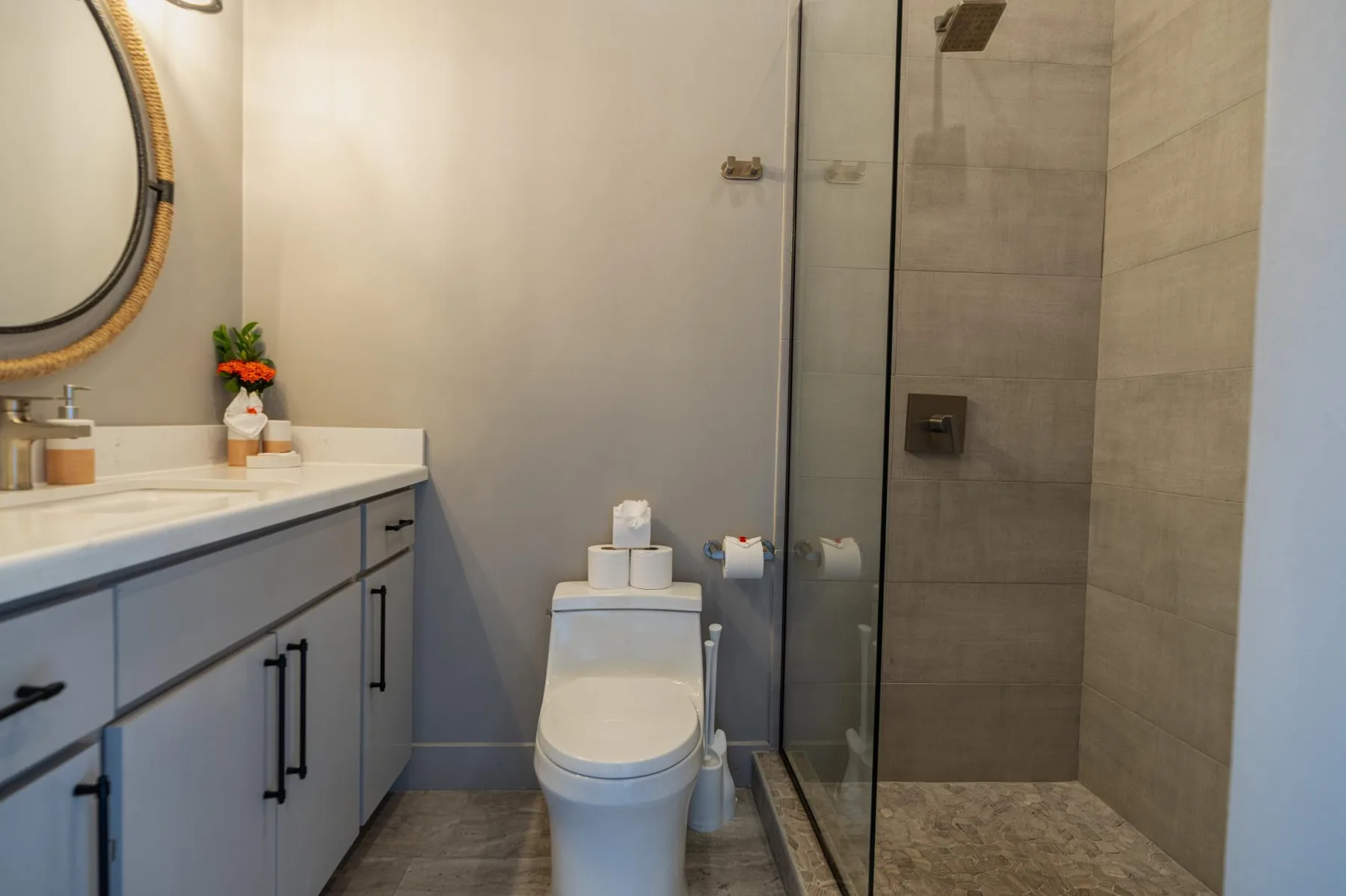 A bathroom with a vanity, toilet, and glass-enclosed shower.
