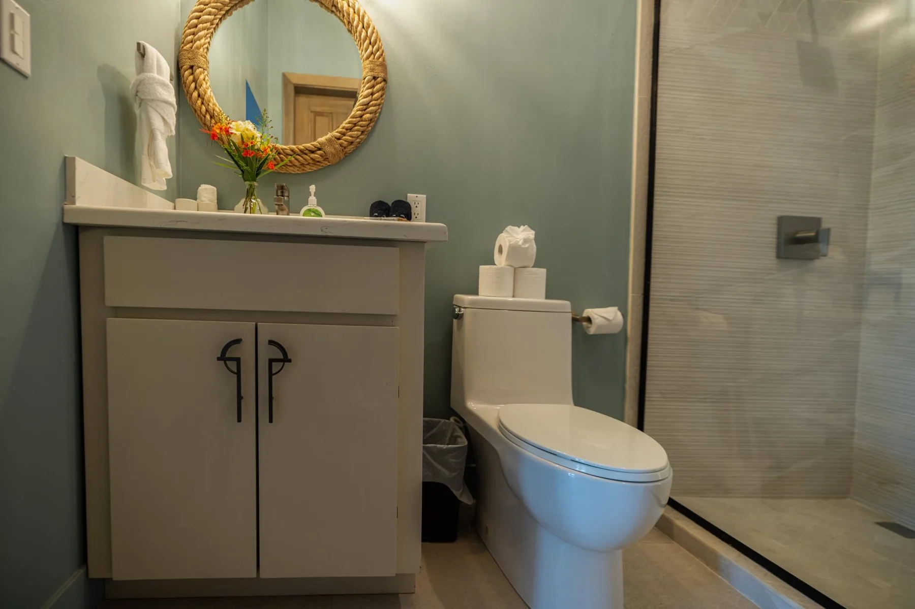 A bathroom with a vanity, toilet, and glass shower.
