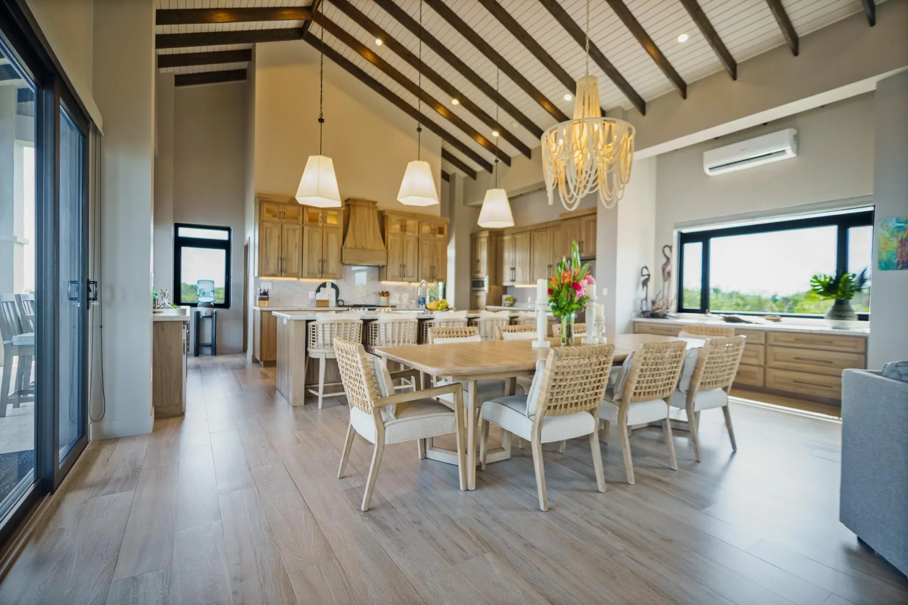 A spacious kitchen and dining area with a wooden table beneath exposed ceiling beams.