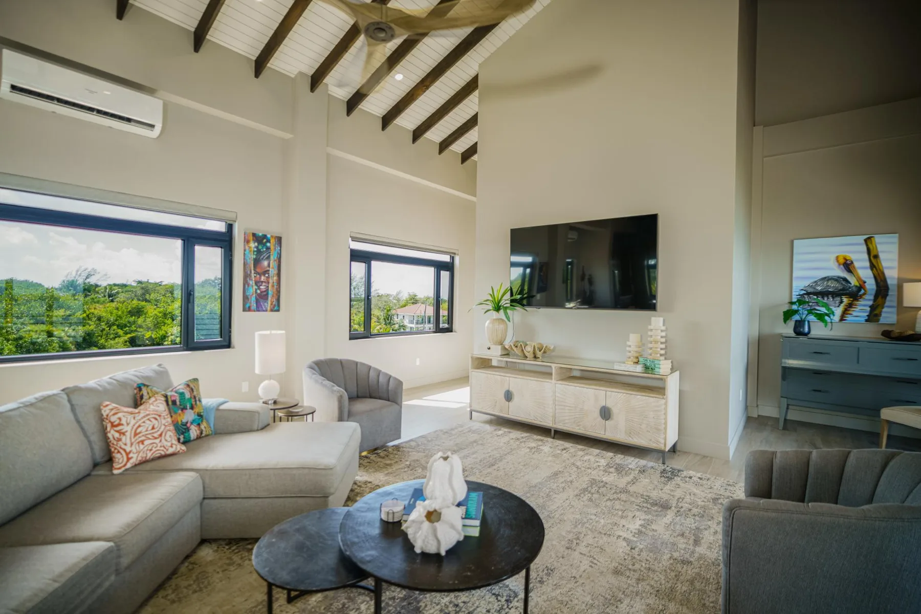 A bright living room with seating, a coffee table, and a wall-mounted television.