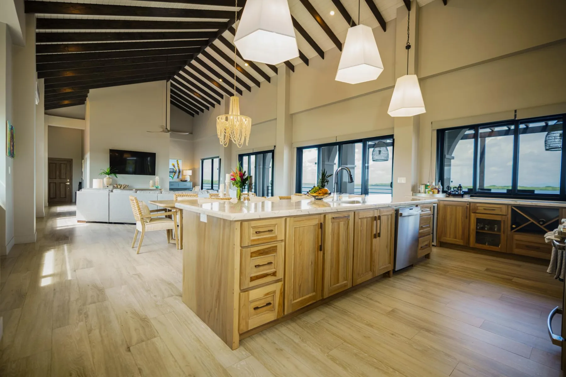A spacious kitchen with a large island, pendant lights, and windows.