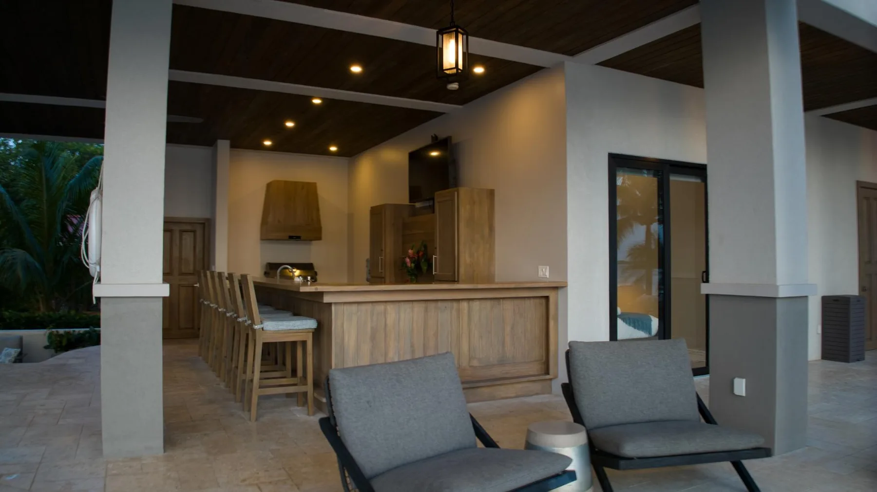 A covered outdoor bar area with a wood counter and seating.