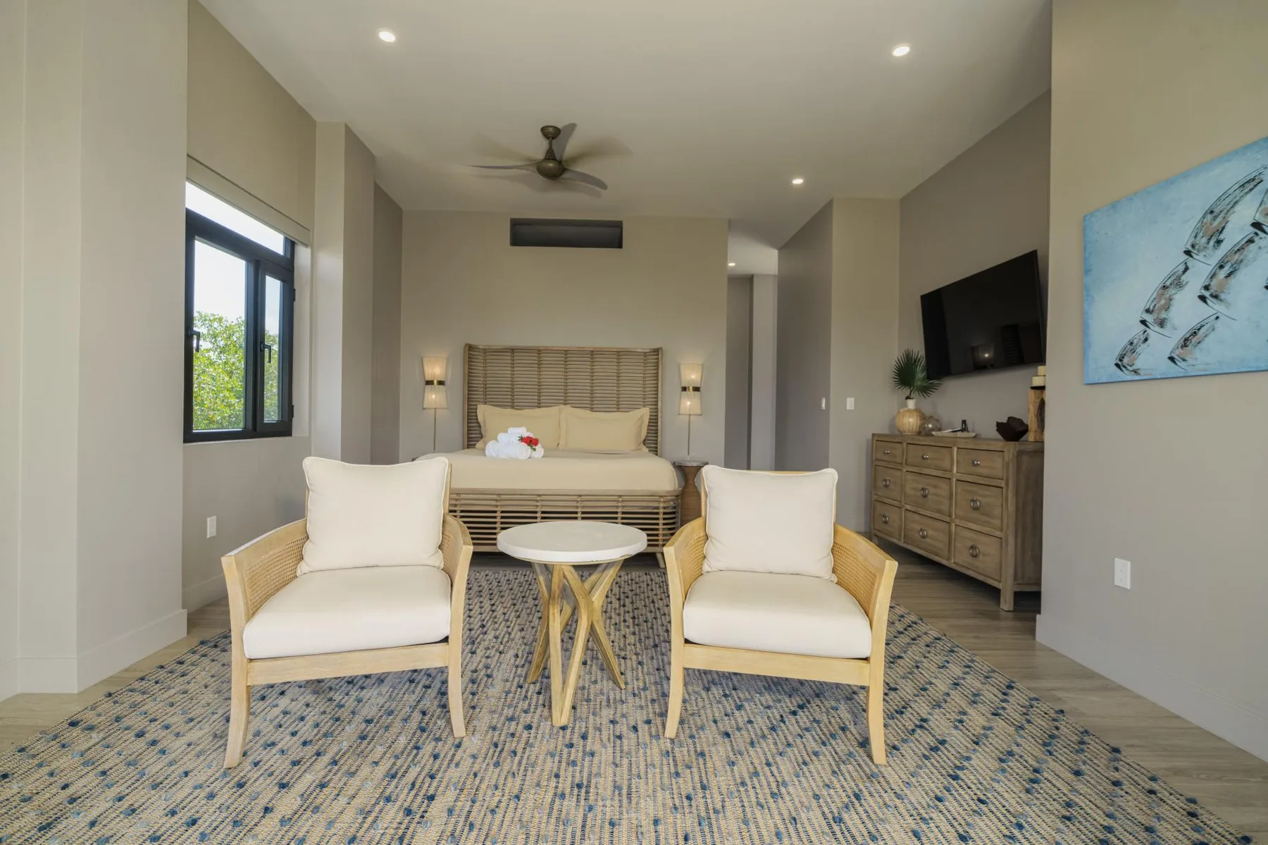 A bedroom with a bed, two armchairs, and a small round table.