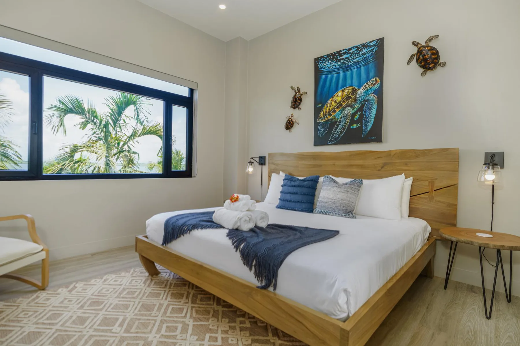 A bedroom with a wooden bed, blue bedding, and a large window.