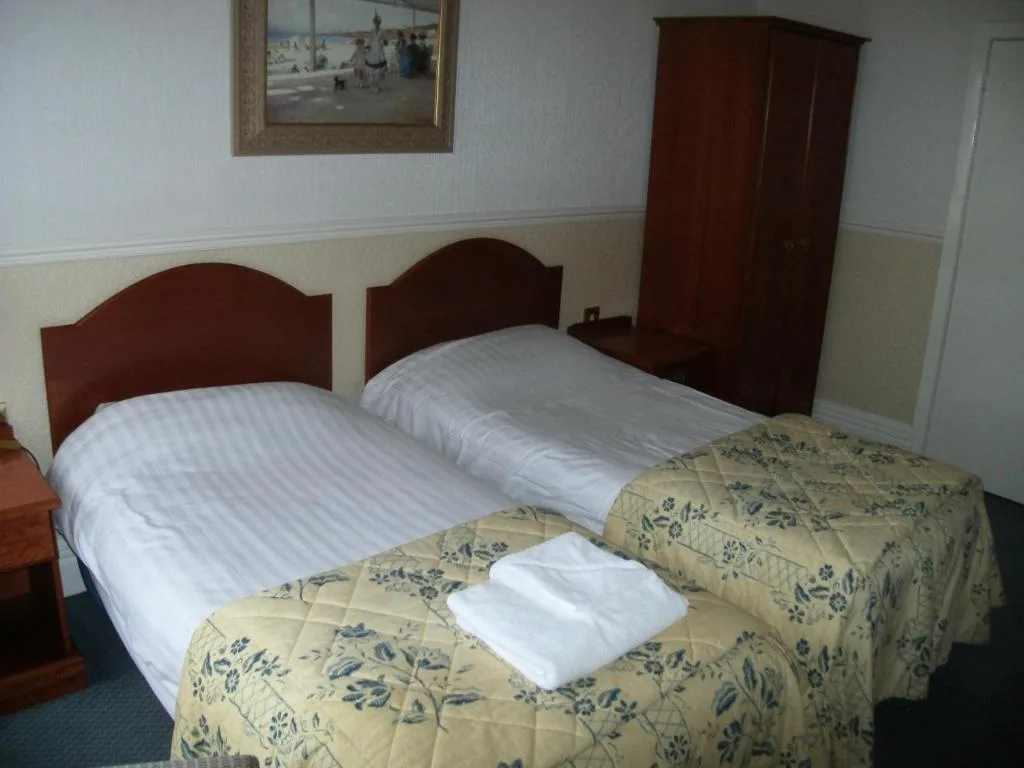 Representative hotel space: A twin bedroom with two beds, patterned bedspreads, and a wooden wardrobe.