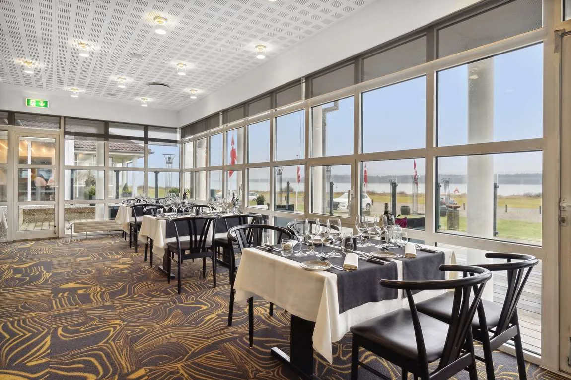 Representative hotel space: A bright dining room with tables set beside large windows.