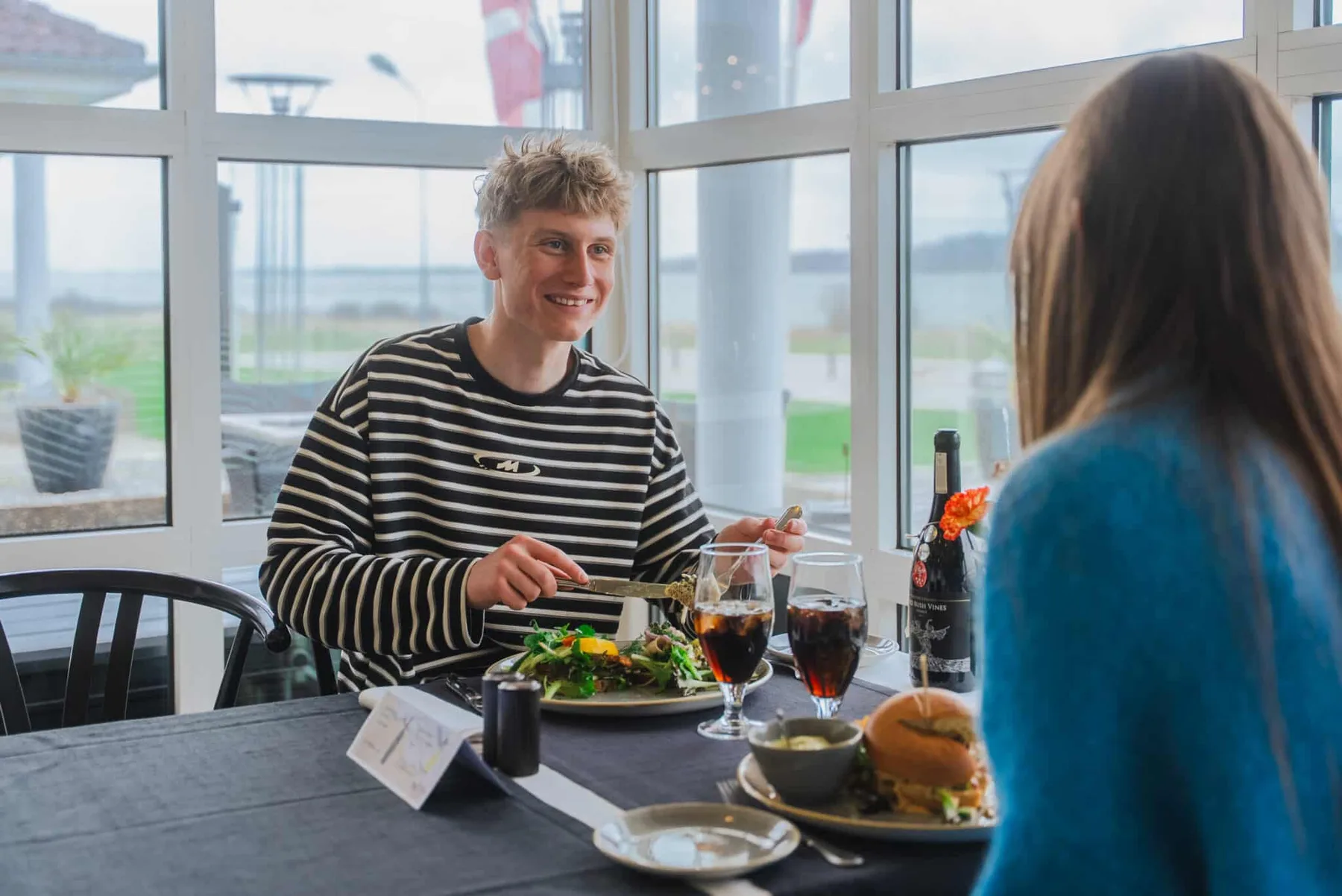 Representative hotel space: Restaurant dining area with two people sharing a meal beside large windows.