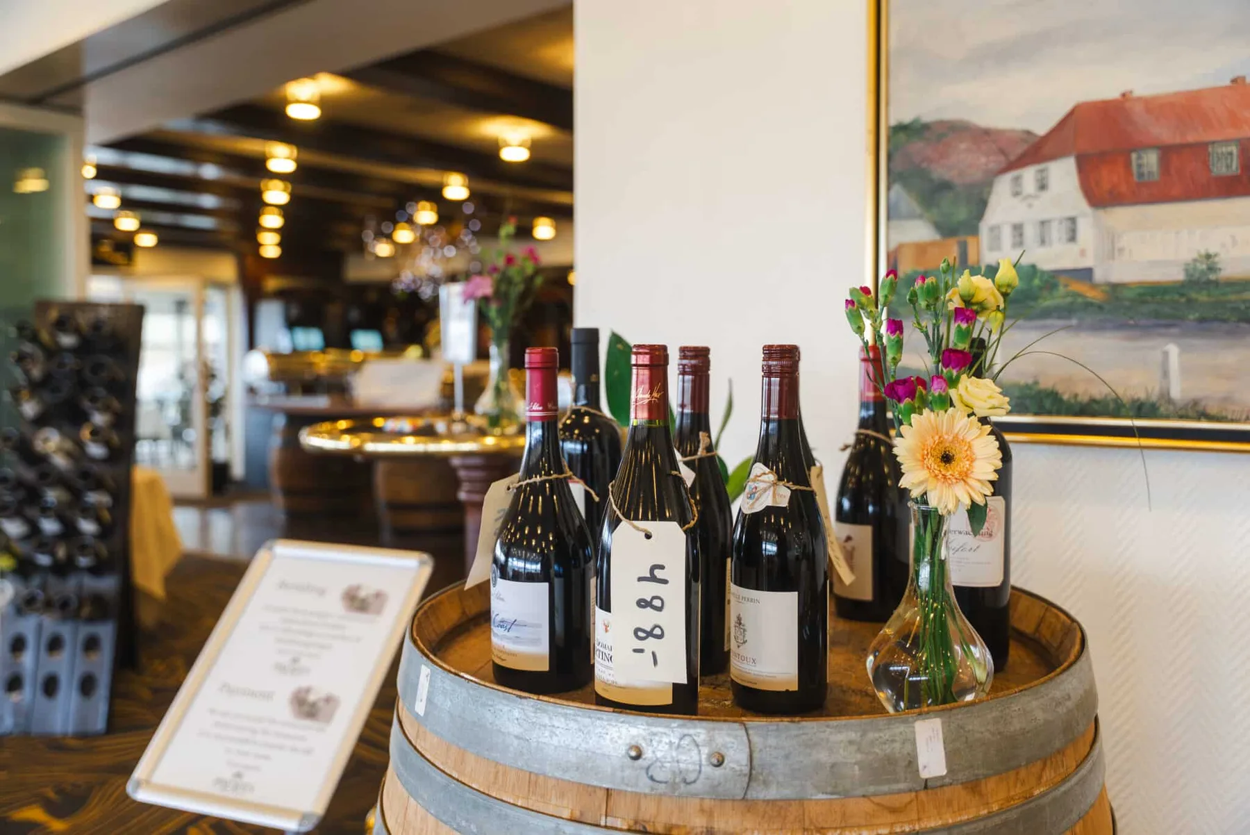 Representative hotel space: A wine display with several bottles and a vase of flowers sits on a wooden barrel.